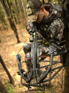 a man in camouflage is aiming an arrow with a bow and arrow rest on the ground