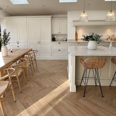 a large kitchen with white cabinets and wooden flooring on the walls, along with two bar stools in front of an island