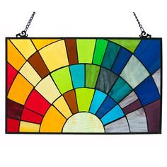 a colorful stained glass window hanging on a metal chain, with the sun in it's center