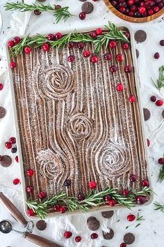 a cake decorated with cranberries and greenery on top of a white table