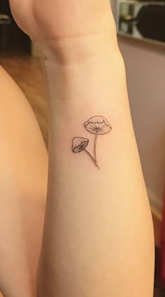 a woman's arm with a small flower tattoo on the left side of her wrist