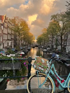 a blue bicycle parked next to a canal filled with flowers and buildings on either side