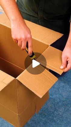 a man is opening a box with a pair of scissors in it and he is cutting the cardboard