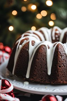 a bundt cake with white icing sitting on a plate next to a christmas tree