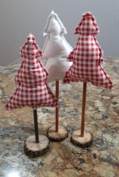 three small trees made out of wood are sitting on a counter top with red and white gingham fabric