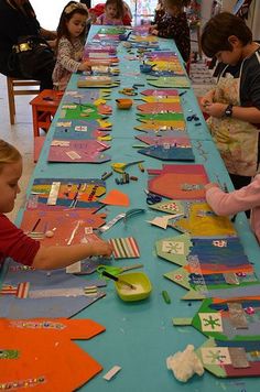 a group of children at a long table with paper cut out to look like kites