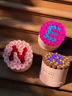 three flower boxes sitting on top of a set of steps with the letters love spelled in them