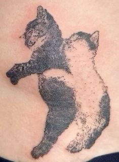 a black and white cat tattoo on the back of a woman's stomach,