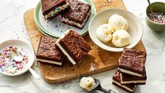 several pieces of cake on a cutting board with ice cream and sprinkles