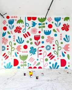 the wall is painted with colorful flowers and plants on it's sides, along with paint rollers