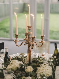 a candelabra filled with white flowers and candles on top of a table