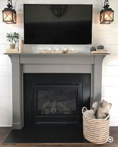 a fireplace with a flat screen tv mounted above it and some baskets on the mantle