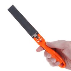 a hand holding an orange handled scissors on a white background