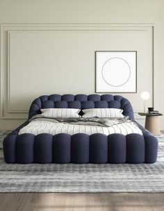 a large bed sitting on top of a wooden floor next to a table and lamp