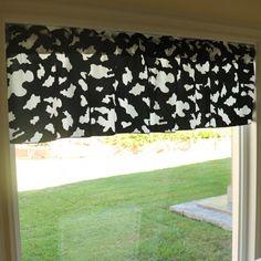 the window is decorated with black and white cow print fabric on it's valance