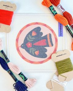 cross - stitch kits and thread laid out on top of a piece of paper with scissors