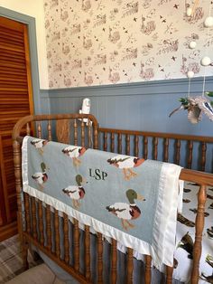 a baby's crib with a personalized blanket on it and ducks hanging from the wall