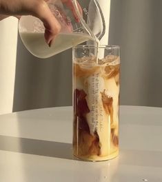 a person pouring milk into a glass filled with ice