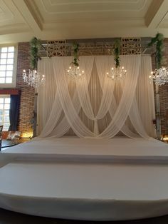 a bed with white sheets and chandelier hanging from the ceiling