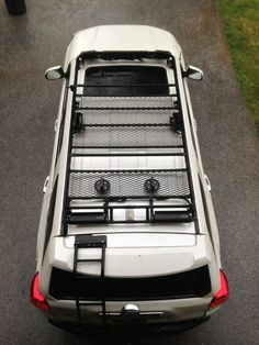 the back end of a white truck parked on top of a parking lot next to grass