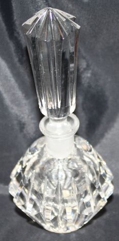 a clear glass perfume bottle sitting on top of a black cloth