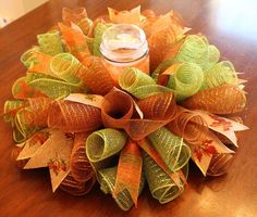 an orange and green wreath sitting on top of a wooden table next to a jar