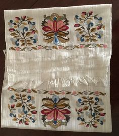 two pieces of white cloth with colorful designs on the sides and fringes hanging from them