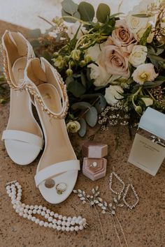 wedding shoes and jewelry on the ground next to flowers, necklaces, and ring