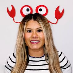 a woman with long blonde hair wearing red eyeballs on her head and smiling at the camera