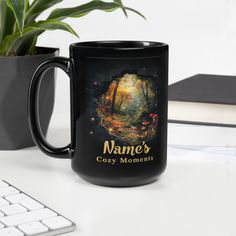 a black coffee mug sitting on top of a desk next to a keyboard and plant