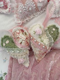 two heart shaped stuffed animals sitting on top of a pink bed sheet covered in lace