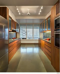 an empty kitchen with stainless steel appliances and wooden cabinetry, along with sliding glass doors