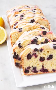 slices of lemon blueberry bread on a white platter next to sliced lemons