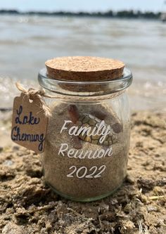 a glass jar filled with sand next to the ocean