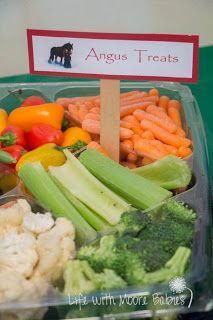 a plastic container filled with assorted veggies next to a sign that says angus treats