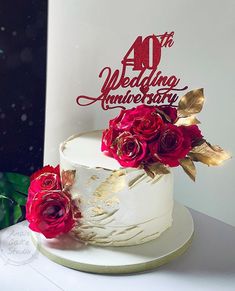 a white cake with red roses on top and a 40 year wedding anniversary sign in the background