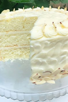 a cake with white frosting and bananas on top sitting on a glass platter