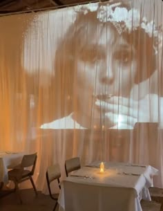 a large photo is projected on the wall behind two tables with white clothed cloths