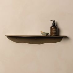 a shelf with a bottle and soap on it next to a wall mounted toothbrush