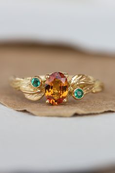 an orange and green ring sitting on top of a leaf