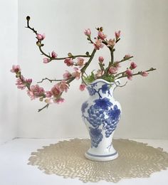 a blue and white vase with pink flowers in it