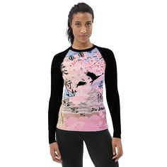 a woman wearing a pink and black top with an image of a bird on it