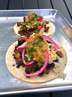 two tortillas with meat, onions and cilantro on a baking sheet