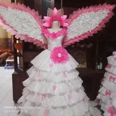 a dress made out of tissue paper with pink flowers on the bottom and white wings