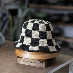 a black and white checkered hat sitting on top of a wooden stand in a shop