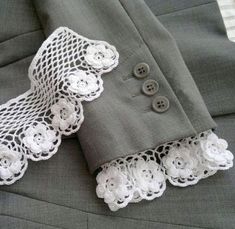 two pieces of clothing with white lace on them and buttons in the middle, sitting on top of a bed