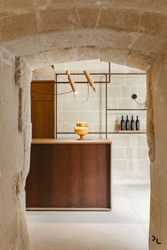 an archway leading into a room with bottles on the counter and shelves in the background