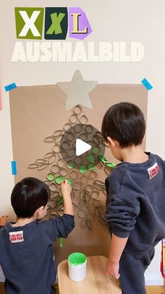 two young boys are making a paper cut out of an animal's head on a piece of cardboard