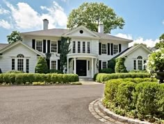 a large white house surrounded by hedges and trees