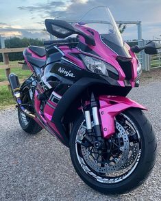 a pink motorcycle parked on top of a gravel road